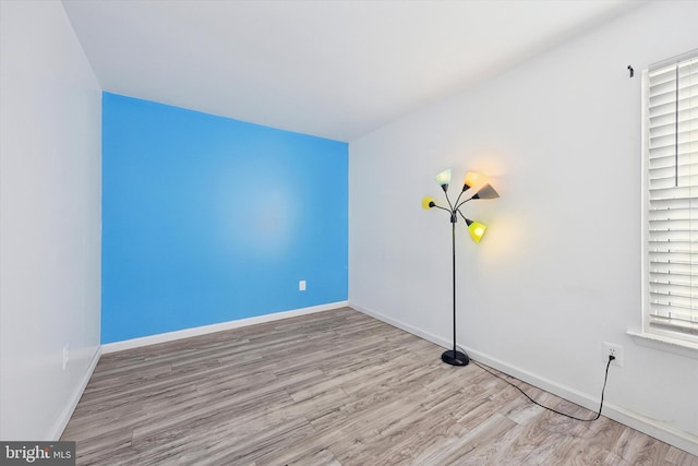 spare room featuring light wood-type flooring and baseboards