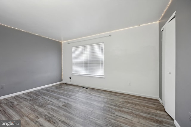 unfurnished bedroom featuring a closet, wood finished floors, visible vents, and baseboards