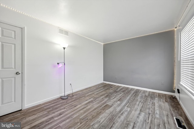 empty room with visible vents, light wood-style flooring, and baseboards