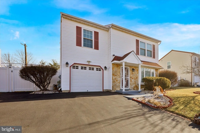 view of front of house featuring aphalt driveway, a garage, fence, stone siding, and a front yard