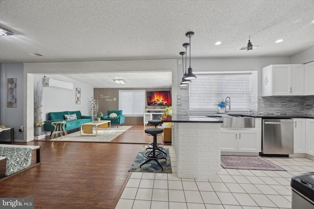 kitchen featuring dark countertops, white cabinetry, open floor plan, and a wall mounted AC