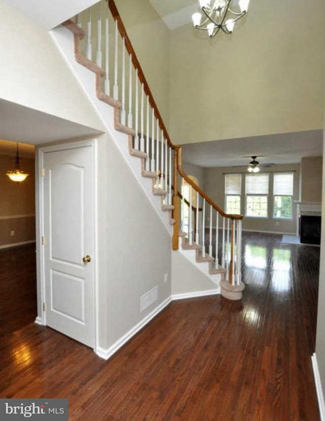 stairs with visible vents, baseboards, hardwood / wood-style floors, a high ceiling, and a fireplace