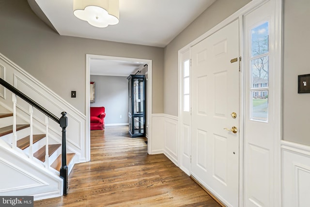 foyer with stairway, wainscoting, and wood finished floors