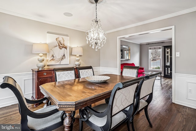 dining area with an inviting chandelier, ornamental molding, wood finished floors, and wainscoting