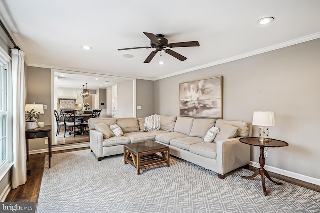 living area with baseboards, wood finished floors, and crown molding