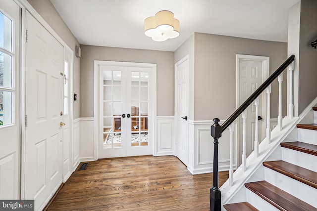 entrance foyer with a wainscoted wall, wood finished floors, french doors, stairway, and a wealth of natural light