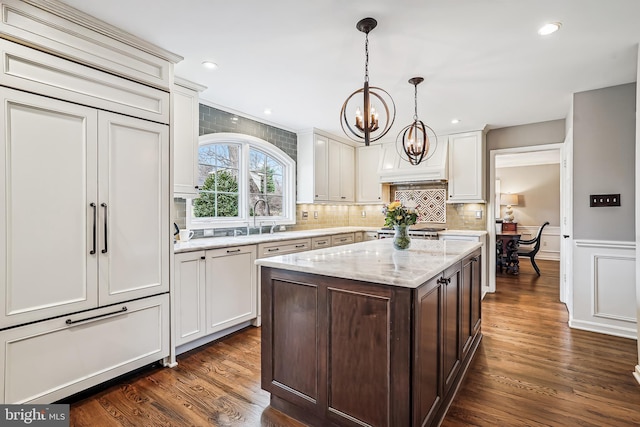 kitchen with white cabinets, a chandelier, dark wood finished floors, and decorative backsplash