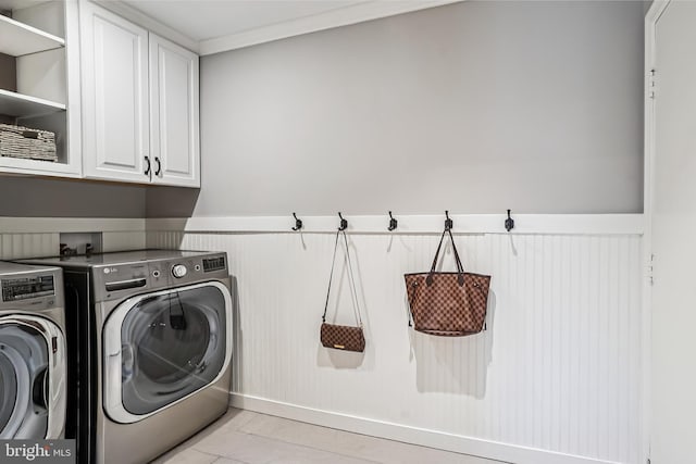 laundry room featuring wainscoting, independent washer and dryer, and cabinet space