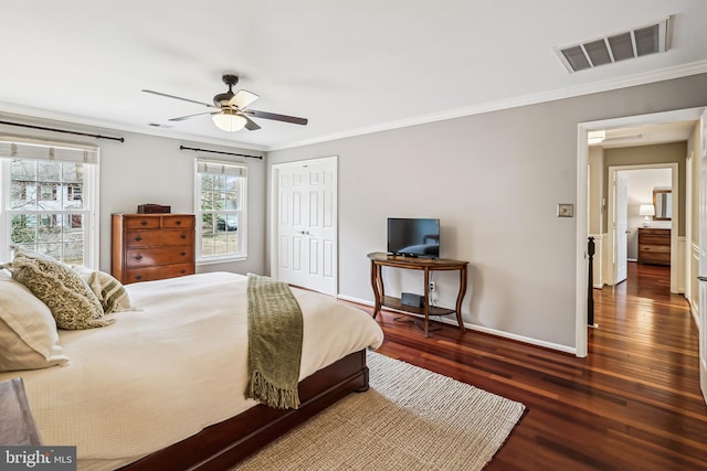 bedroom featuring baseboards, crown molding, visible vents, and wood finished floors