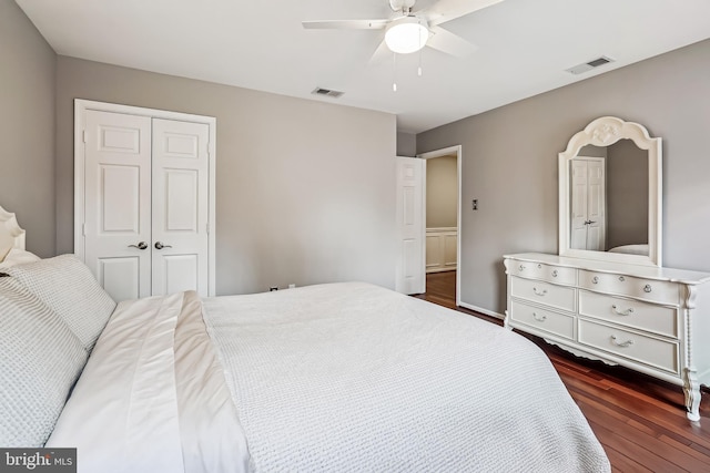 bedroom with dark wood-type flooring, a closet, visible vents, and a ceiling fan