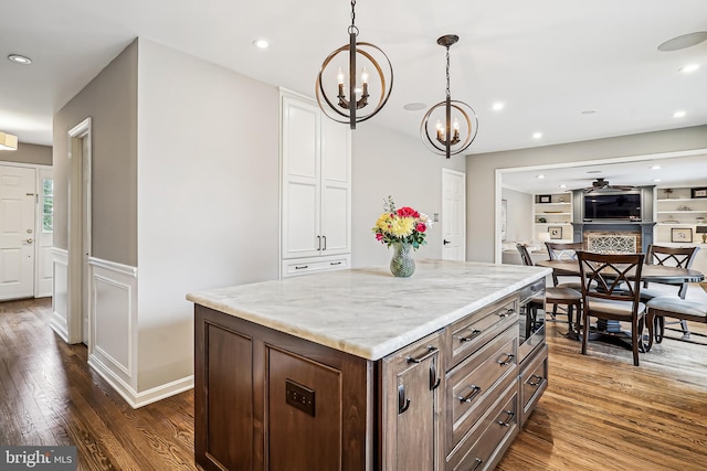 kitchen featuring dark wood-style floors, built in shelves, light stone counters, recessed lighting, and hanging light fixtures