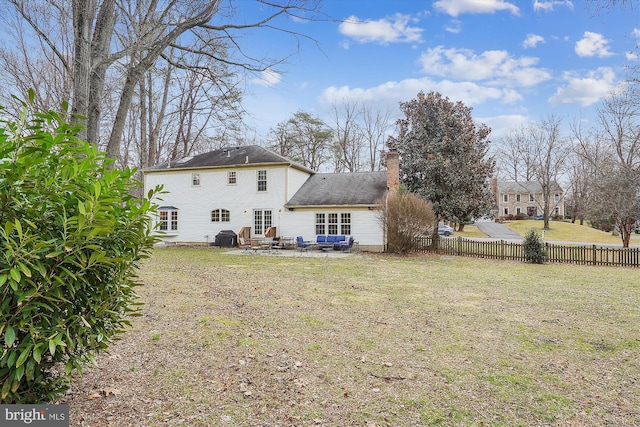 rear view of house with a chimney, a lawn, a patio area, and fence