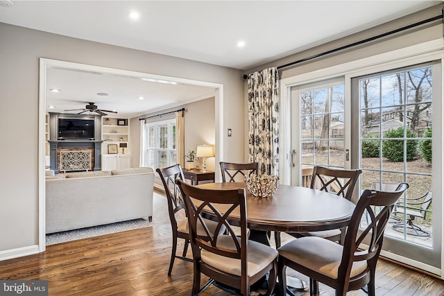 dining area featuring baseboards, ceiling fan, wood finished floors, a fireplace, and recessed lighting