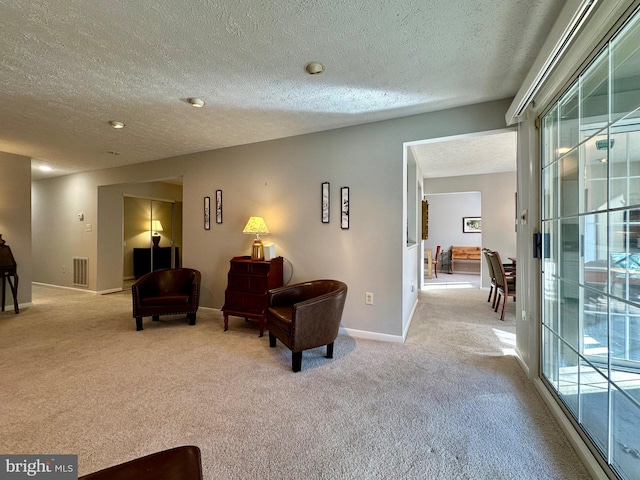 sitting room with baseboards, visible vents, and light colored carpet