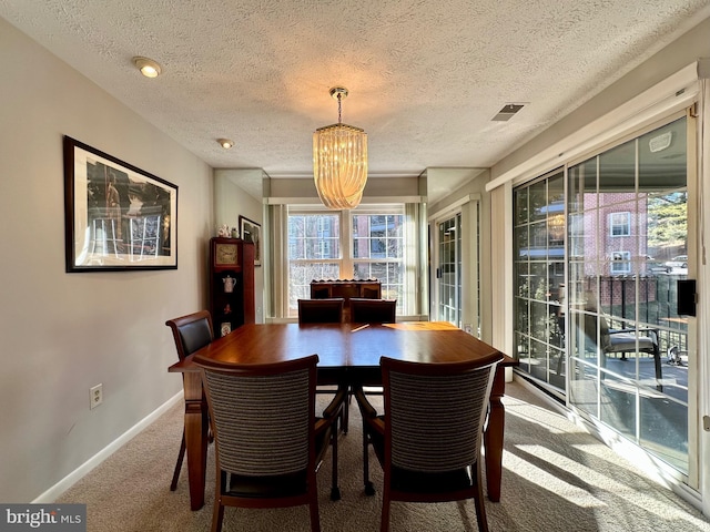 carpeted dining room featuring a textured ceiling and baseboards