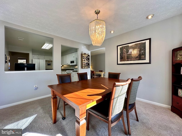 carpeted dining space featuring a notable chandelier, a textured ceiling, and baseboards