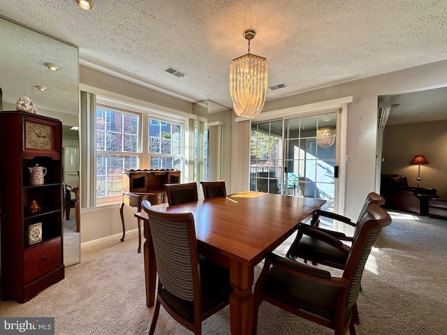 dining space with light carpet, baseboards, visible vents, and a notable chandelier