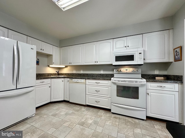 kitchen with white appliances, stone finish floor, a sink, and white cabinets