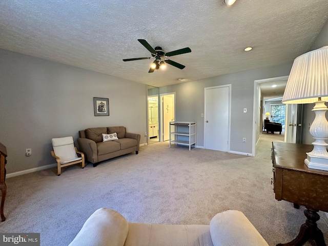 living room featuring baseboards, a textured ceiling, and light colored carpet