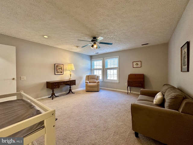 living area featuring ceiling fan, a textured ceiling, carpet floors, visible vents, and baseboards