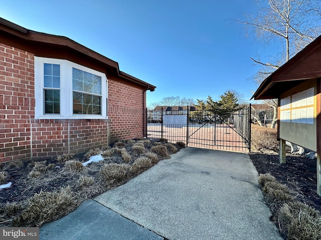 view of home's exterior featuring a gate, fence, and brick siding