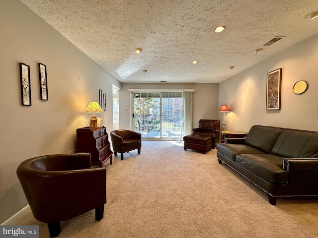 living area with recessed lighting, light colored carpet, visible vents, and a textured ceiling