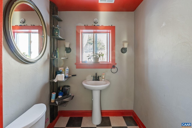 bathroom with baseboards, visible vents, toilet, and tile patterned floors