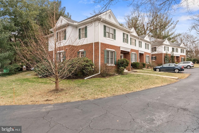 view of front of house featuring brick siding, a front lawn, and stucco siding