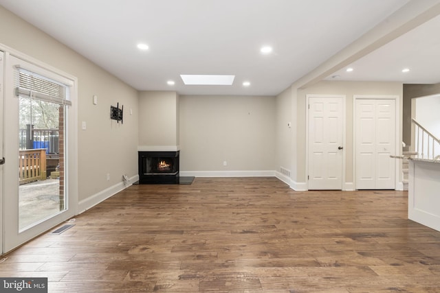 unfurnished living room with a skylight, wood finished floors, visible vents, and recessed lighting