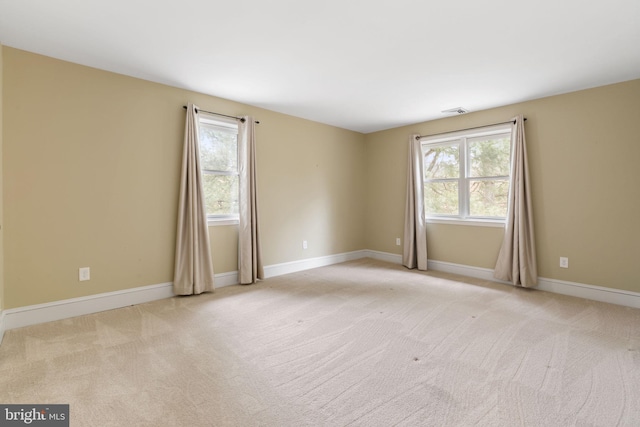 unfurnished room featuring light colored carpet, plenty of natural light, and baseboards