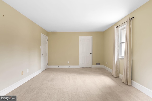 spare room featuring visible vents, baseboards, and light colored carpet