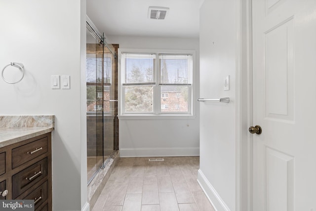 bathroom featuring baseboards, vanity, visible vents, and a shower stall