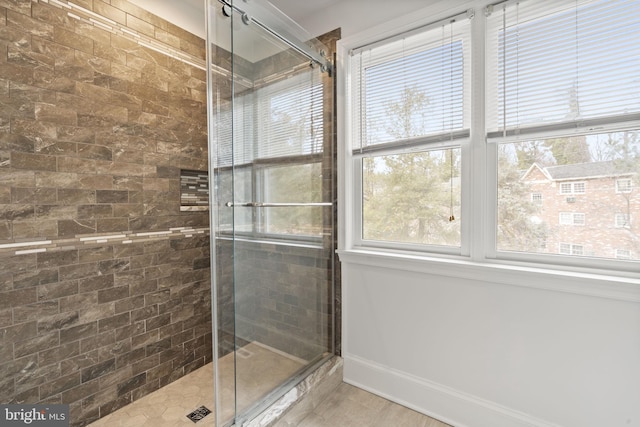 full bath featuring baseboards and tiled shower