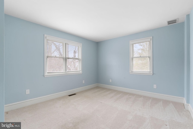 spare room featuring baseboards, visible vents, and light colored carpet