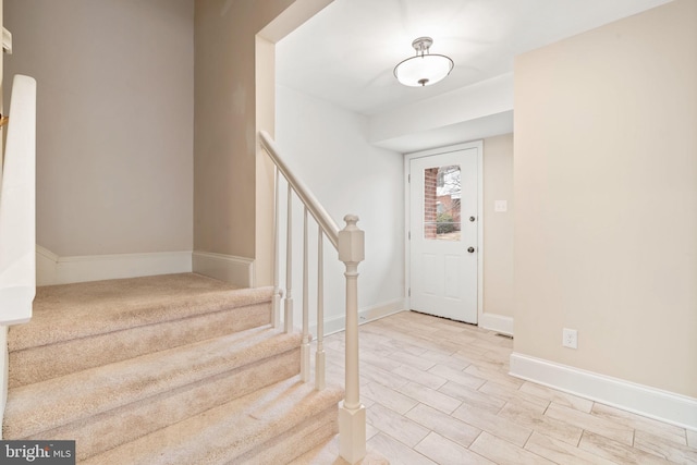 foyer entrance featuring stairway and baseboards