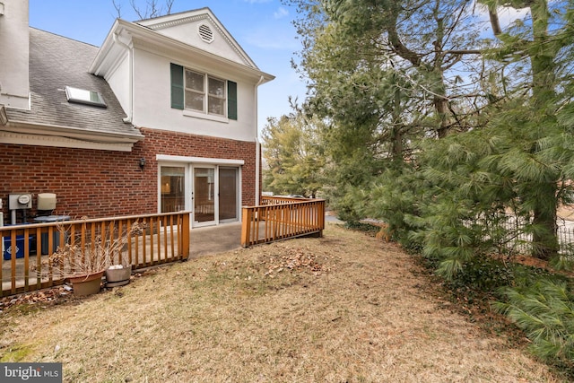 back of property featuring stucco siding, brick siding, and a wooden deck