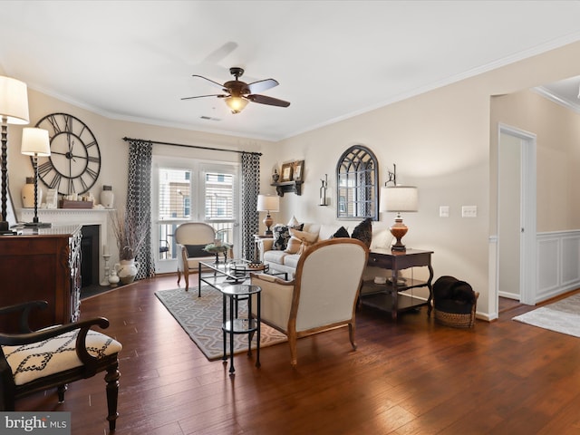 living room with visible vents, dark wood finished floors, a glass covered fireplace, ceiling fan, and ornamental molding