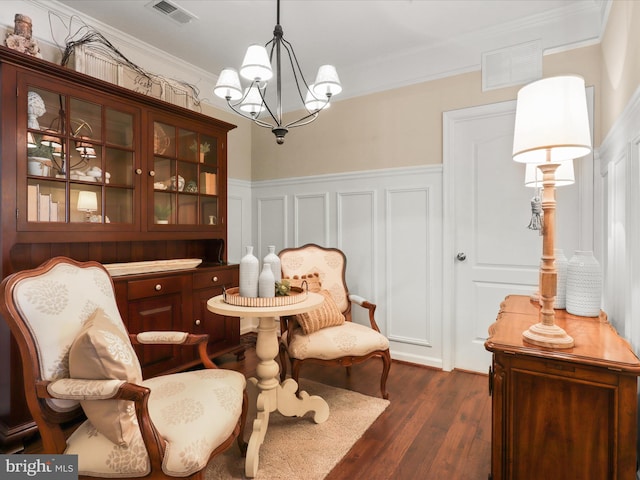 sitting room featuring dark wood-style floors, visible vents, crown molding, and an inviting chandelier