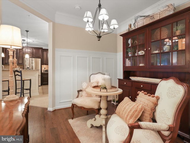 living area with ornamental molding, wainscoting, a notable chandelier, and dark wood-style floors