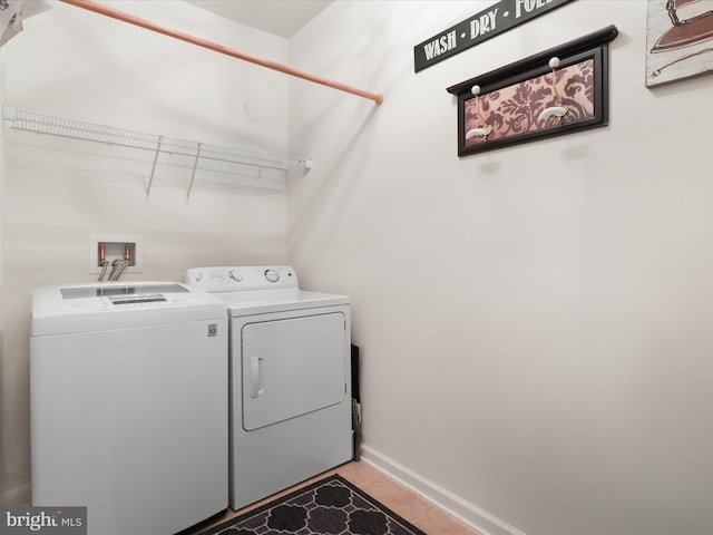 clothes washing area featuring laundry area, light tile patterned floors, baseboards, and washer and clothes dryer