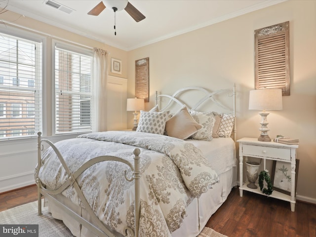 bedroom featuring ornamental molding, dark wood finished floors, visible vents, and a ceiling fan