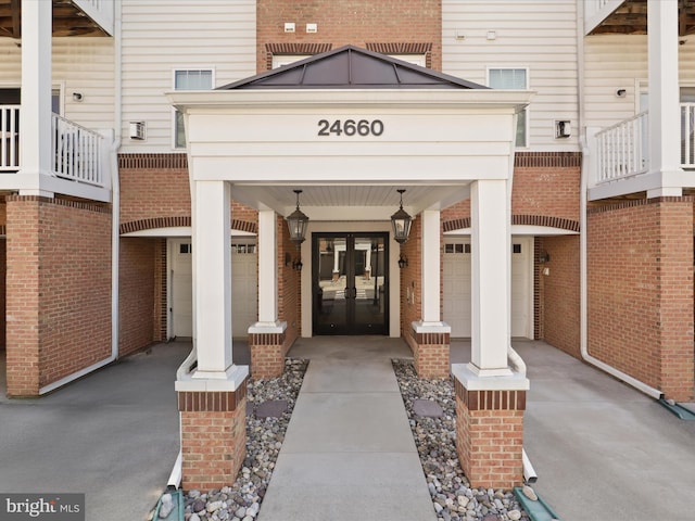 view of exterior entry featuring driveway, french doors, and brick siding