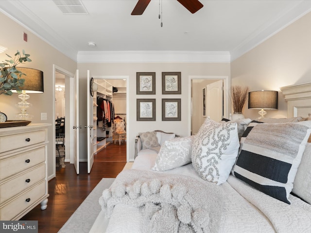 bedroom with ornamental molding, dark wood-style flooring, a walk in closet, and visible vents