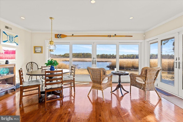 dining room featuring a water view, visible vents, crown molding, and french doors