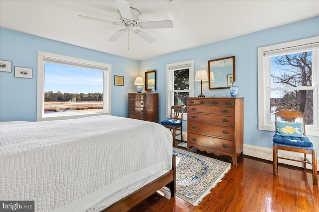 bedroom featuring dark wood-style floors, a baseboard radiator, baseboards, and ceiling fan