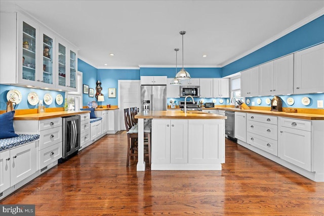 kitchen with a center island with sink, glass insert cabinets, stainless steel appliances, white cabinetry, and a sink