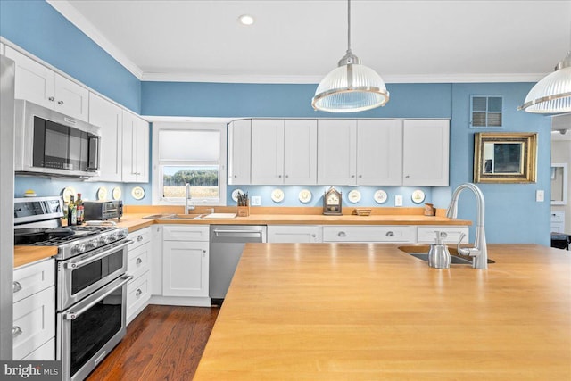 kitchen featuring stainless steel appliances, white cabinets, hanging light fixtures, and wooden counters