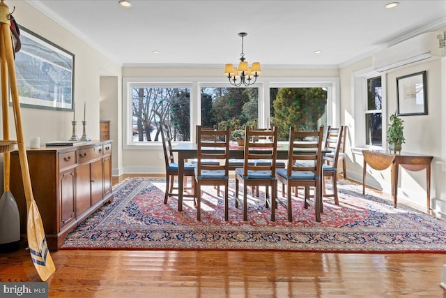 dining room featuring ornamental molding, an AC wall unit, an inviting chandelier, and wood finished floors