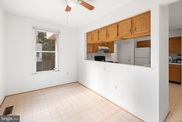 kitchen featuring light floors, visible vents, freestanding refrigerator, under cabinet range hood, and black / electric stove