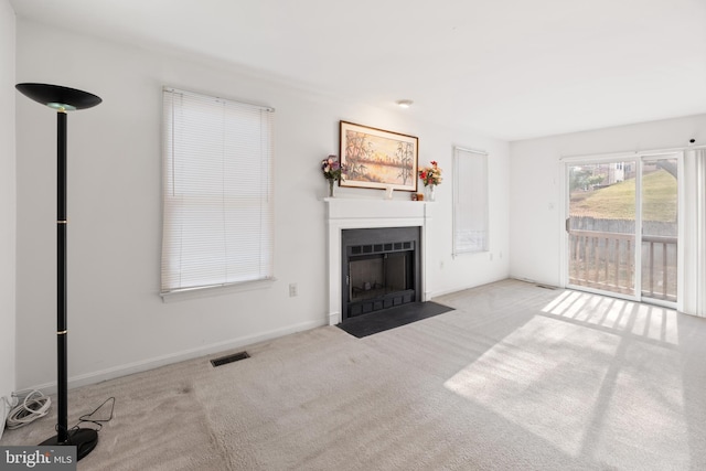 unfurnished living room featuring carpet floors, baseboards, visible vents, and a fireplace with flush hearth